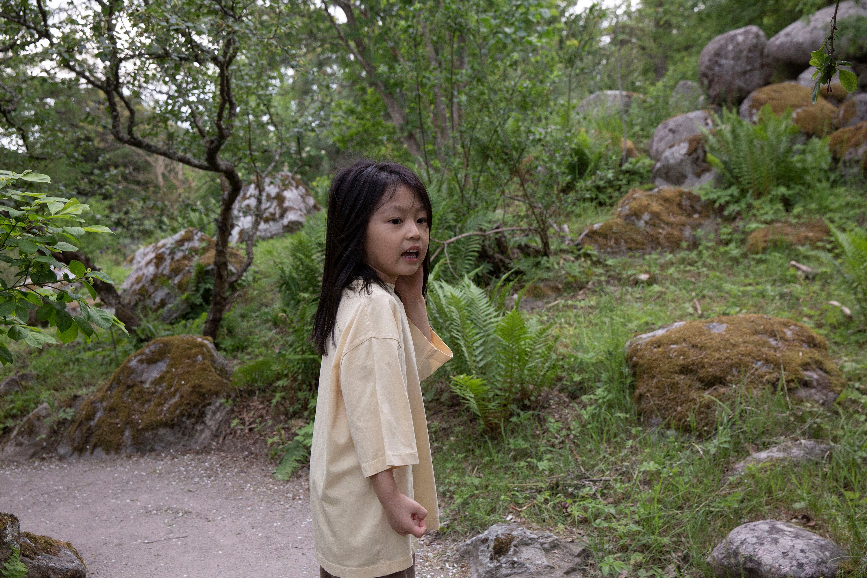 Façade Bato Wide Tee in butter worn by a child, organic cotton oversized kids t-shirt styled outdoors among greenery
