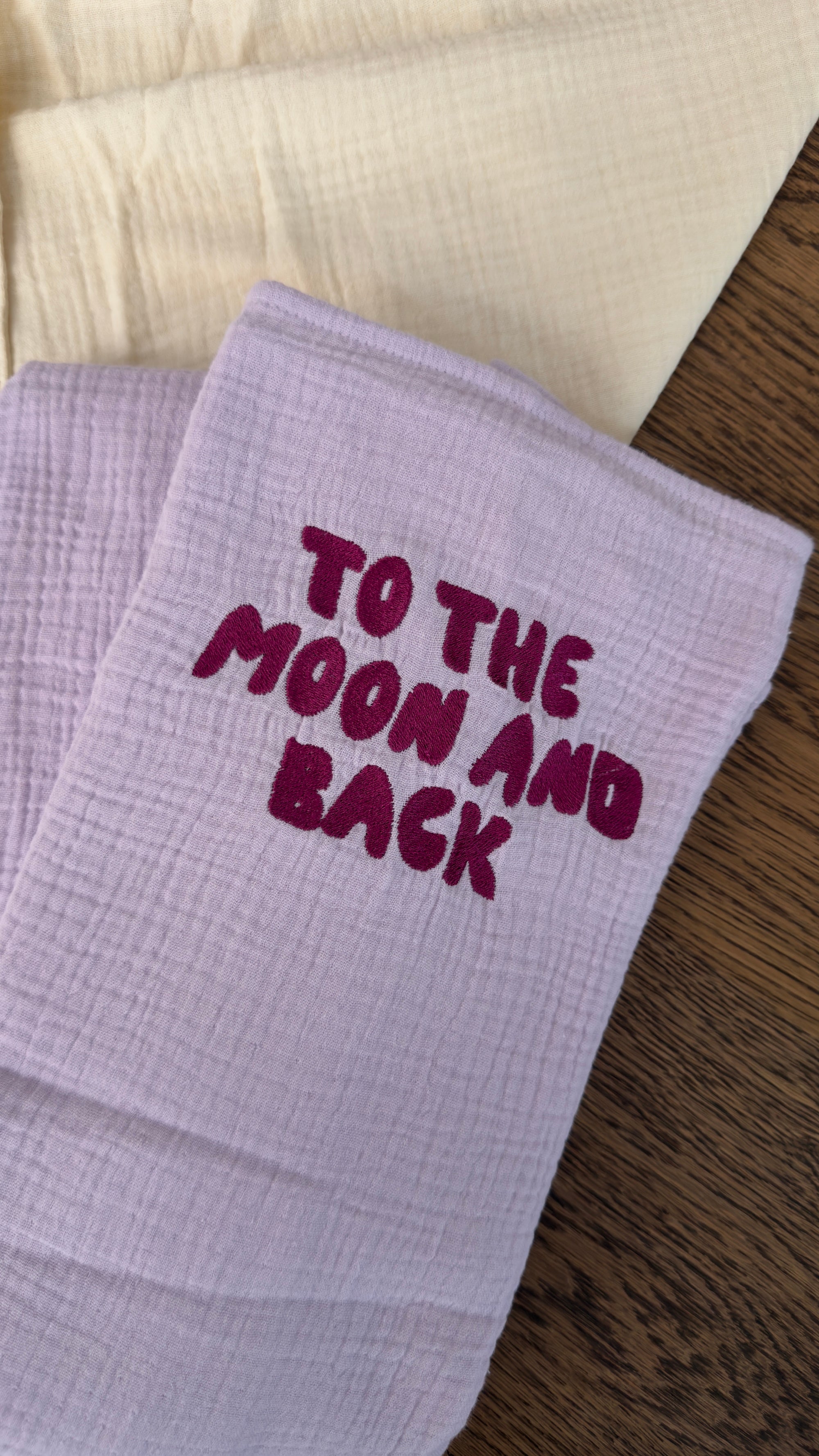 120x120 organic muslin giant swaddle in Lucky Lila with “To The Moon And Back” embroidery