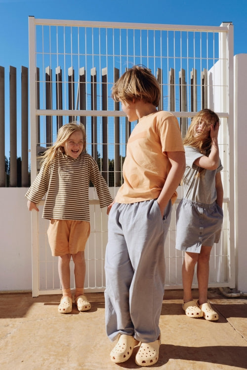 Child sitting and wearing Gray Label's Zipper cardigan and Grey trousers