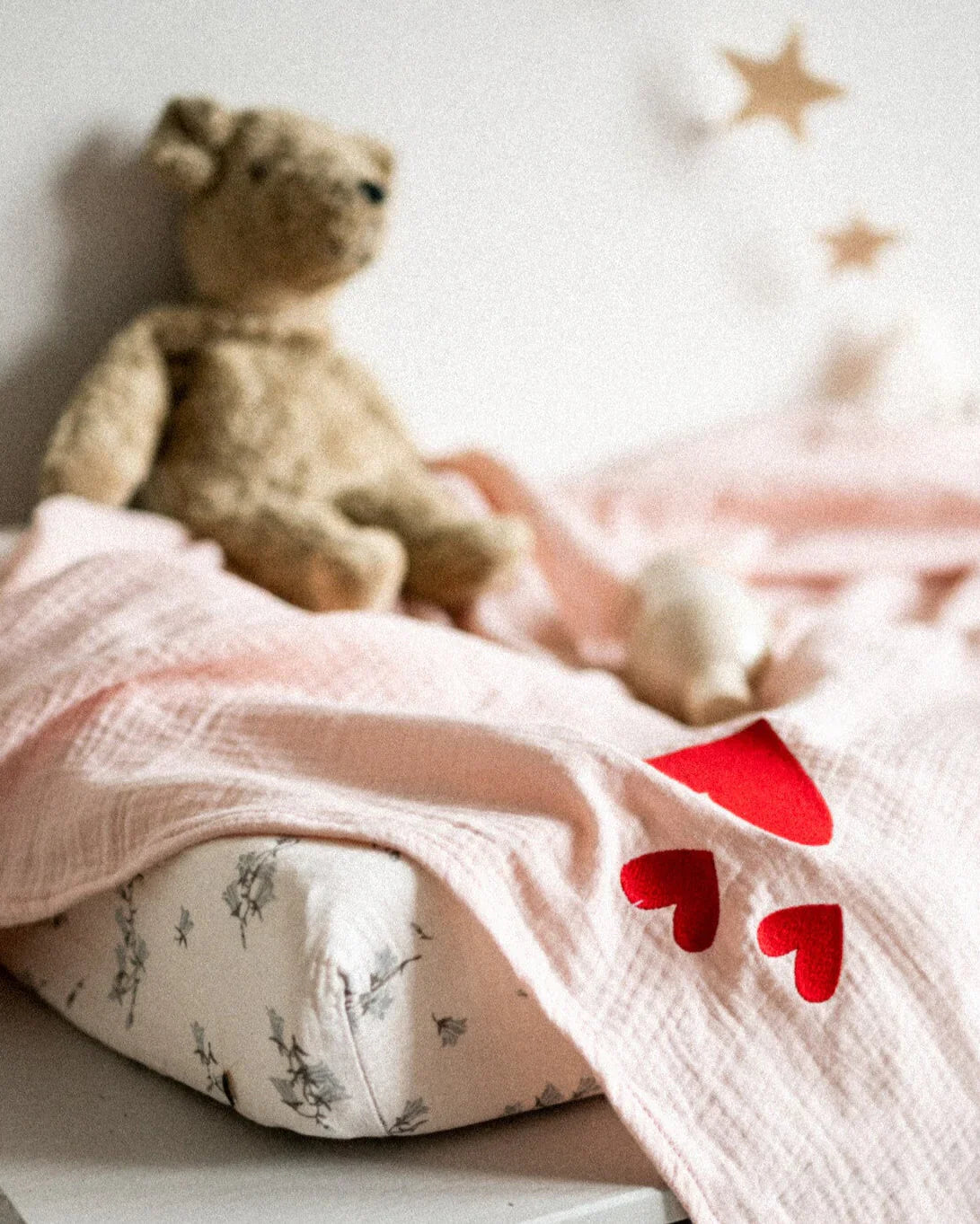 Teddybear on baby changing pad with light pink blanket with lovehearts