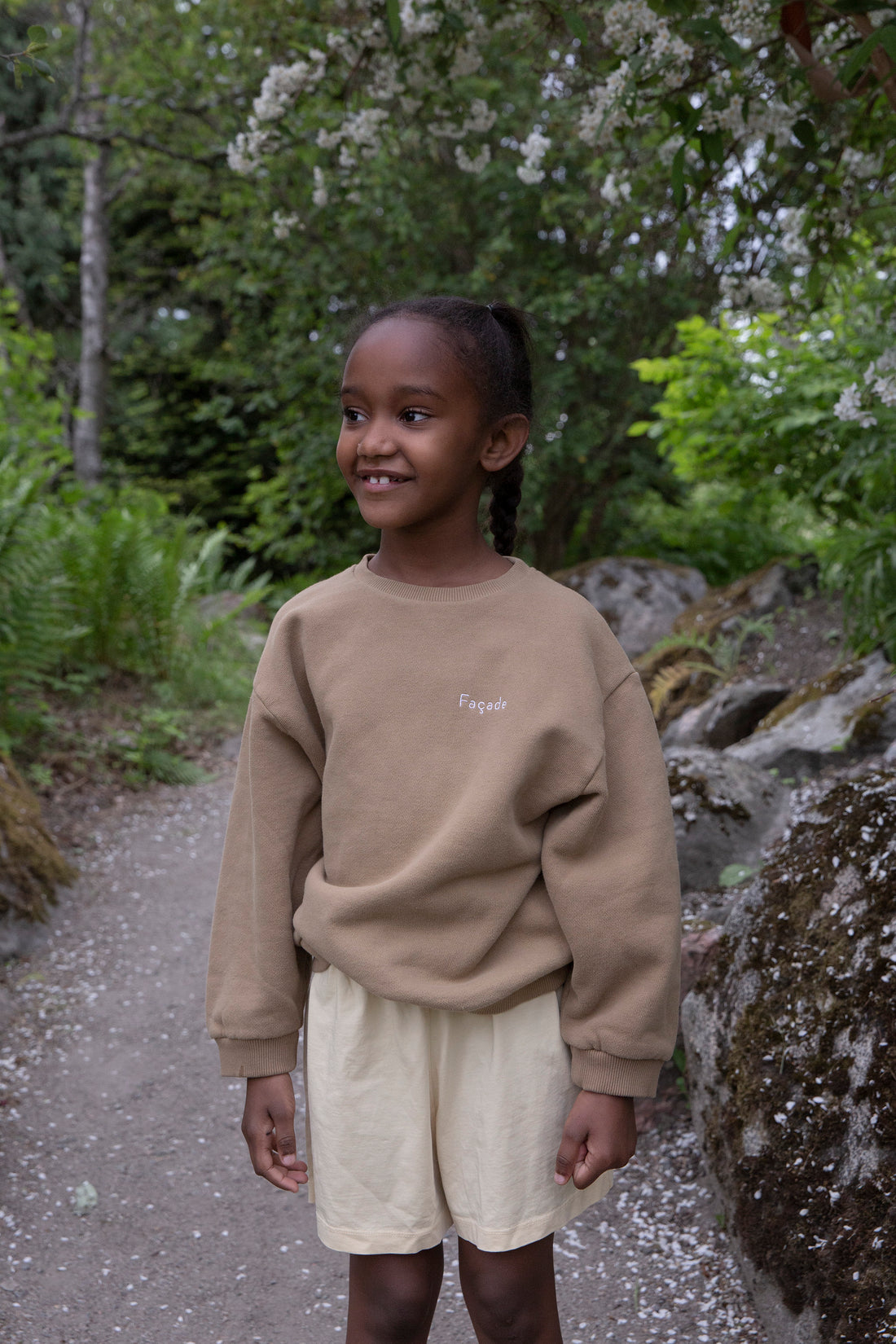 Child wearing Façade Mido Runner Shorts in butter and Hama Chunky Sweatshirt in hay, organic cotton kids outfit styled outdoors