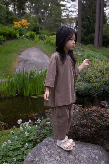 Façade Bato Wide Tee and Kohi Wide Pants in mole, worn by a child, outdoor in a park near the pond
