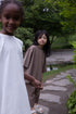 Children wearing Façade Bato Wide Tee and Kohi Wide Pants in mole, organic cotton oversized kids clothing, photographed outdoors in a park