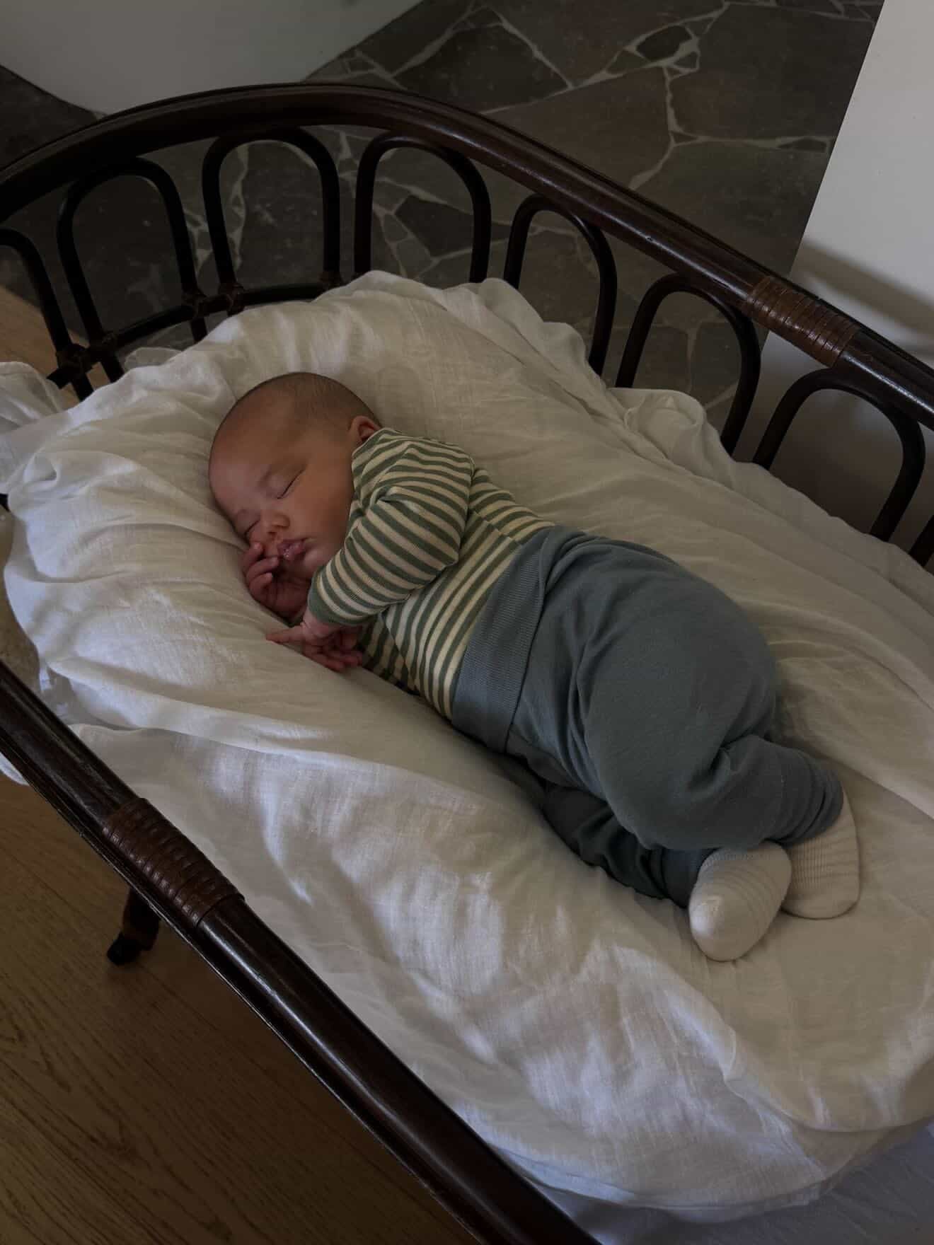 Sleeping baby wearing Engel Natur Wool Silk baby pants in mountain blue and merino wool bodysuit in sage natural