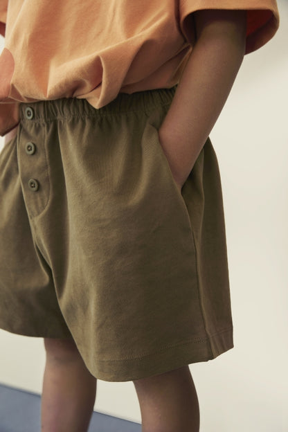 Detail of decorative button on organic cotton jersey shorts