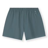 Organic cotton jersey shorts made from GOTS-certified cotton, shown in blue grey colour. Showing logo on the back side. 