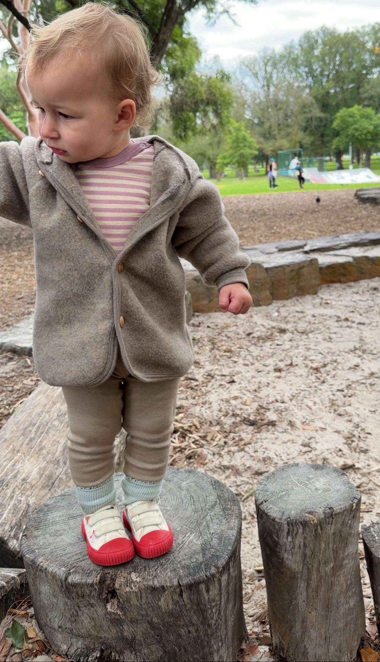 Child wearing Engel Natur merino wool fleece jacket in walnut melange and merino wool bodysuit in Rosewood melange 