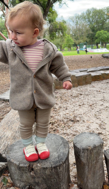 Child wearing Engel Natur merino wool fleece jacket in walnut melange and merino wool bodysuit in Rosewood melange 