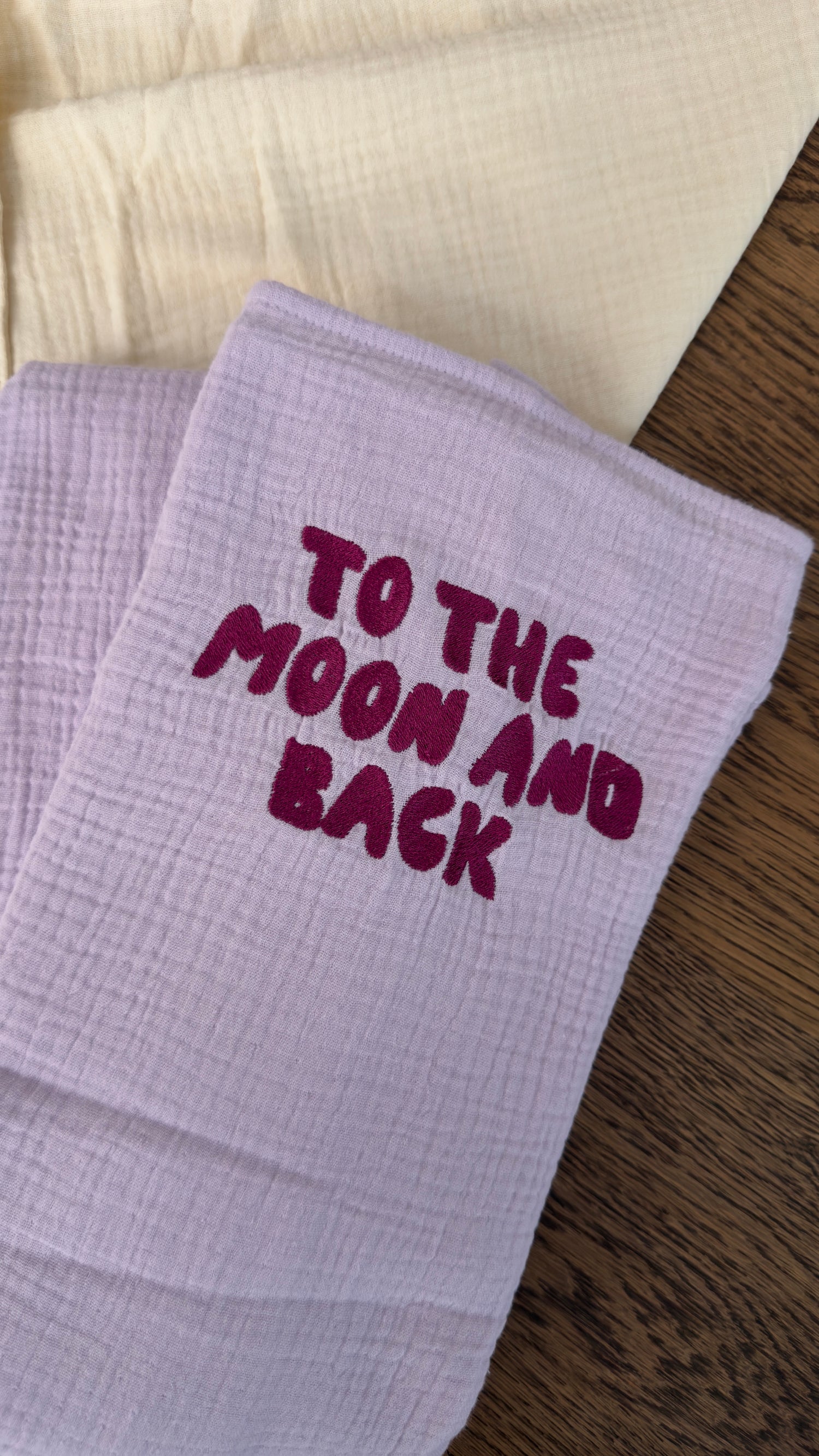 120x120 organic muslin giant swaddle in Lucky Lila with “To The Moon And Back” embroidery