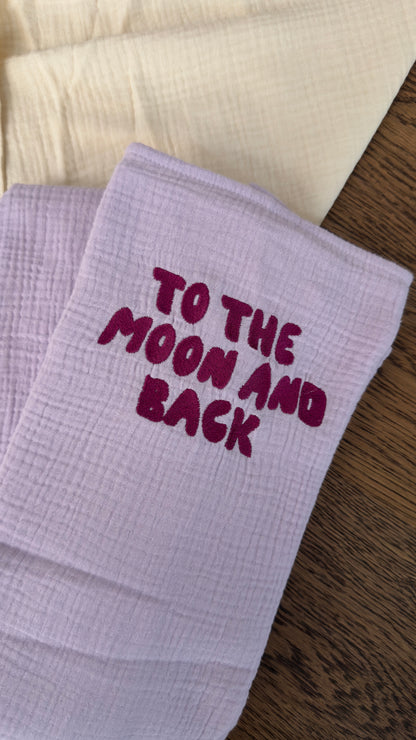 120x120 organic muslin giant swaddle in Lucky Lila with “To The Moon And Back” embroidery