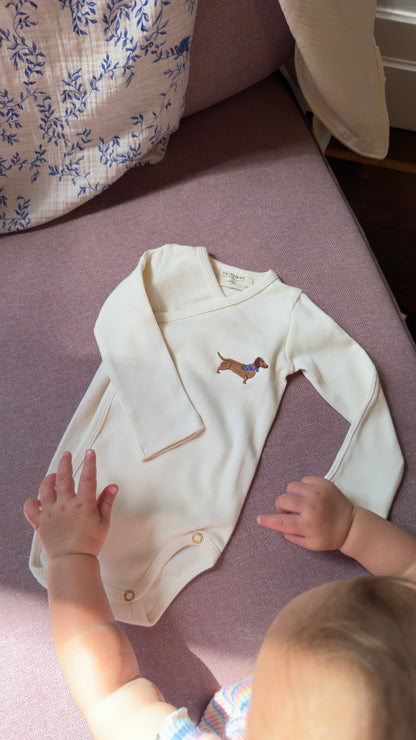 Organic cotton wrap baby bodysuit in Cozy White with sausage dog embroidery