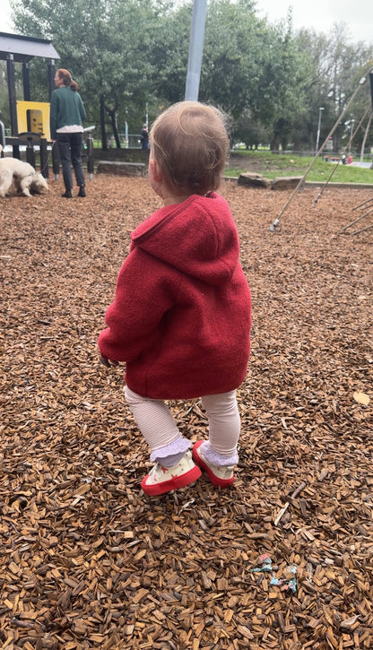 Child in playground wearing Gray Label Leggings in color faded pink and Red jacket