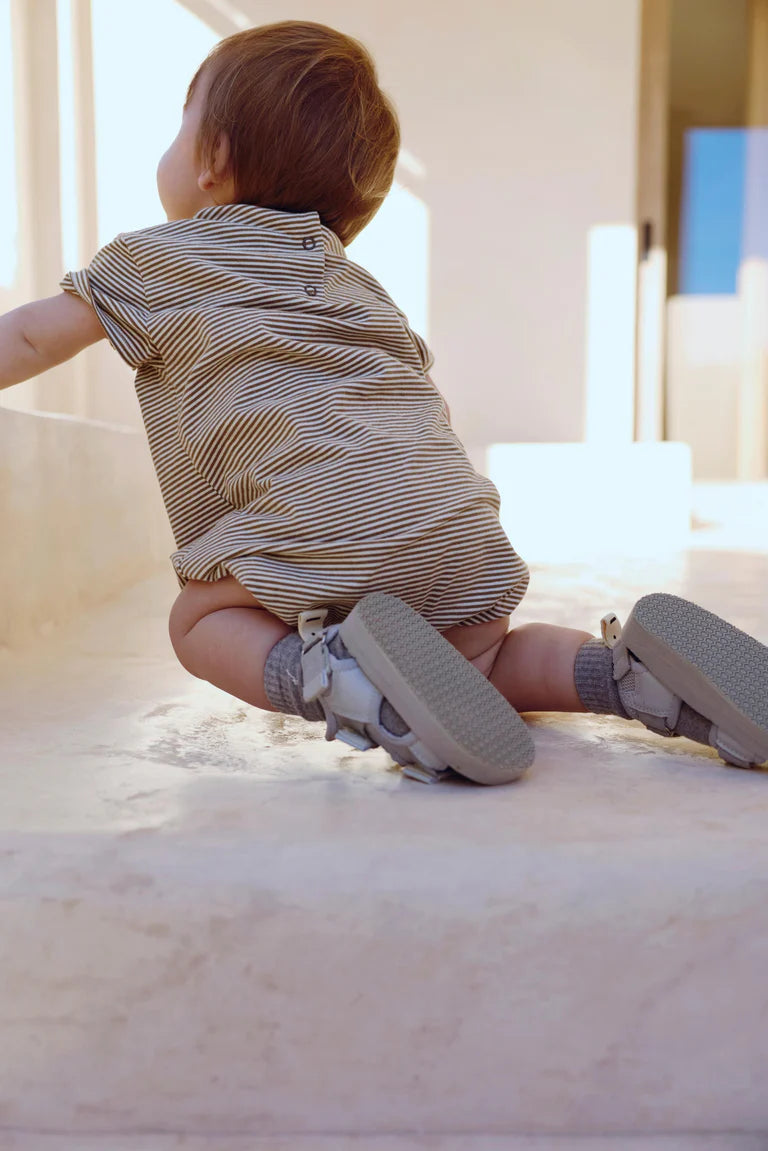 Baby wearing Gray Label organic cotton baby tee suit in Woody Cream