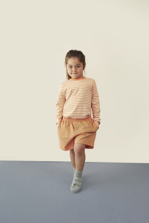 Child wearing Gray Label organic cotton jersey shorts in Melon
