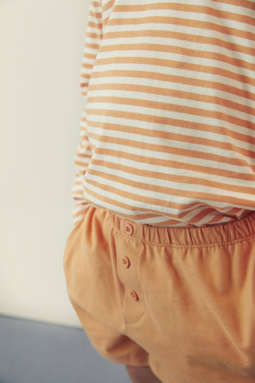 Detail of decorative button on organic cotton jersey Gray Label shorts in melon