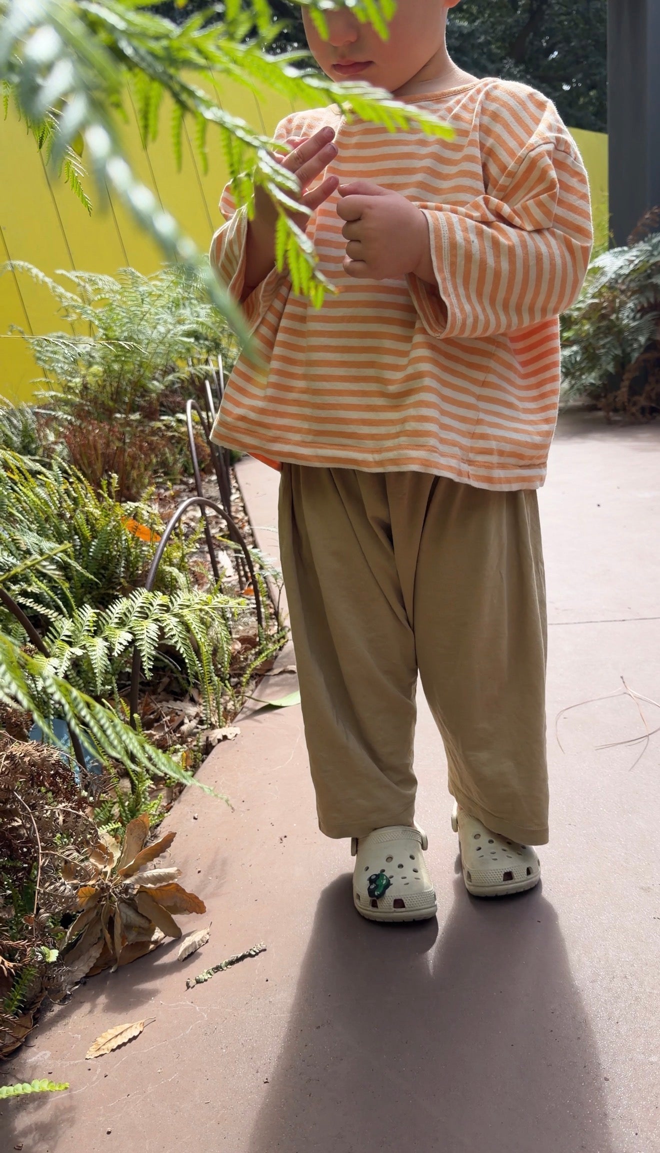 Child in garden wearing Gray Label organic cotton oversized tee in Melon Cream